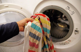ep una persona introduce ropa sucia en una lavadora