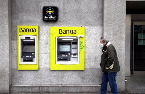 ep archivo - un hombre con mascarilla pasa por delante de un cajero de bankia
