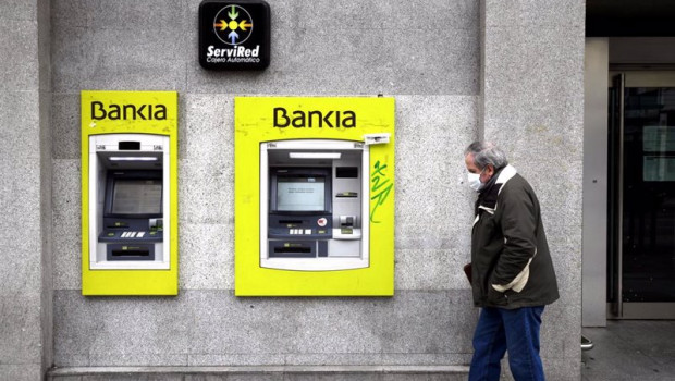 ep archivo - un hombre con mascarilla pasa por delante de un cajero de bankia