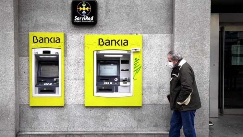 ep archivo - un hombre con mascarilla pasa por delante de un cajero de bankia