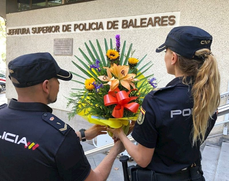 ep dos agentes sostienen el ramo de flores depositado en la jefatura superior de policia de baleares