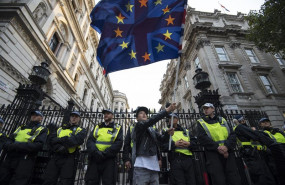 ep un chico ondea una bandera de la union europea y de reino unido frente a un grupo de policias