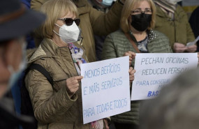 ep dos mujeres sostienen unas pancartas en un acto simbolico de denuncia de la exclusion financiera