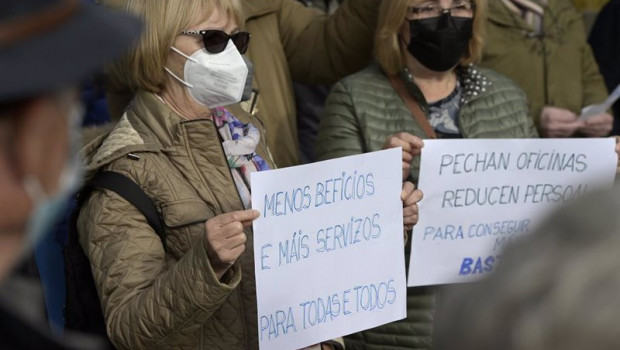 ep dos mujeres sostienen unas pancartas en un acto simbolico de denuncia de la exclusion financiera