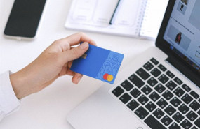 ep una persona utilizando su tarjeta de credito para realizar compras online con un ordenador