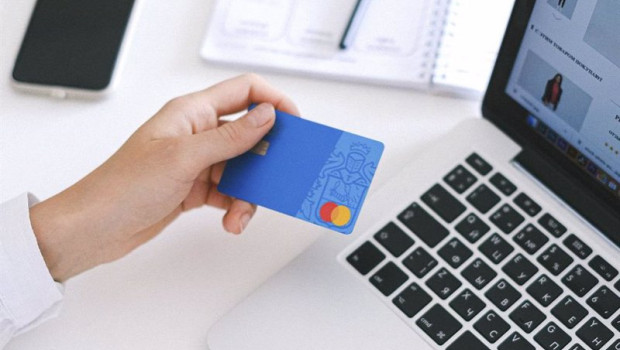 ep una persona utilizando su tarjeta de credito para realizar compras online con un ordenador