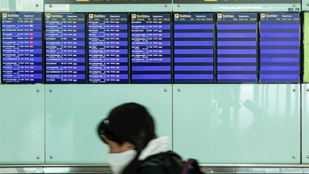 ep una pasajera con mascarilla observa los paneles del aeropuerto el prat de barcelona