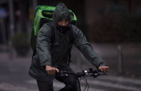 ep un rider repartidor trabaja bajo la lluvia protegido con un impermeable en sevilla andalucia