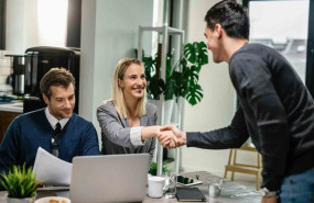 1656664338 two financial advisors having meeting with young man at home female advisor is shaking hands with client