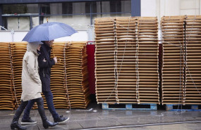 ep archivo   una pareja pasea bajo su paragua con las sillas apiladas de fondo durante la vuelta de