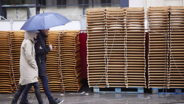 ep archivo   una pareja pasea bajo su paragua con las sillas apiladas de fondo durante la vuelta de