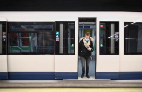 ep una mujer protegida con mascarilla se baja de uno de los metros de la capital en un anden con