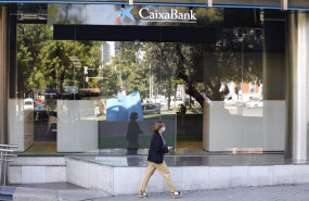 ep una mujer pasa por al lado de las oficinas de caixabank en el paseo castellana en madrid espana a