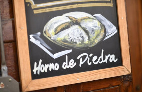 ep una pizarra con un dibujo de una hogaza de pan en la que se lee horno de piedra