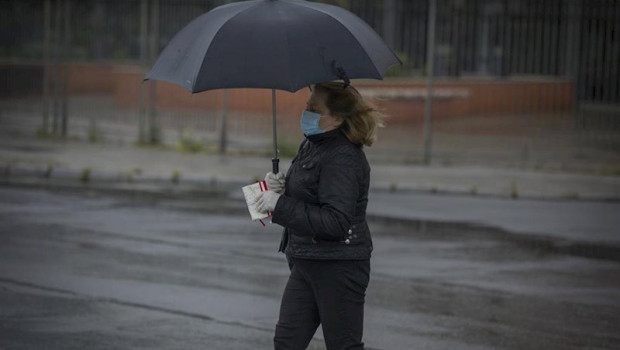 ep una mujer bajo un paraguas en sevilla durante el estado de alarma por la crisis del coronavirus