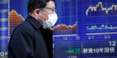 bourse-un-homme-portant-un-masque-passe-devant-un-tableau-electronique-montrant-des-graphiques-de-recents-mouvements-de-l-indice-nikkei