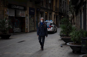 ep un hombre con mascarilla pasea por una calle de barcelona junto a un coche de la policia en el