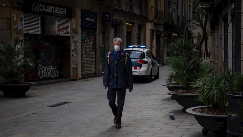 Un hombre con mascarilla pasea por una calle de Barcelona junto a un coche de la Policía en el segundo día laborable del estado de alarma por el coronavirus, en Barcelona (España), a 17 de marzo de 2020. | David Zorrakino - Europa Press - Archivo ep un hombre con mascarilla pasea por una calle de barcelona junto a un coche de la policia en el
