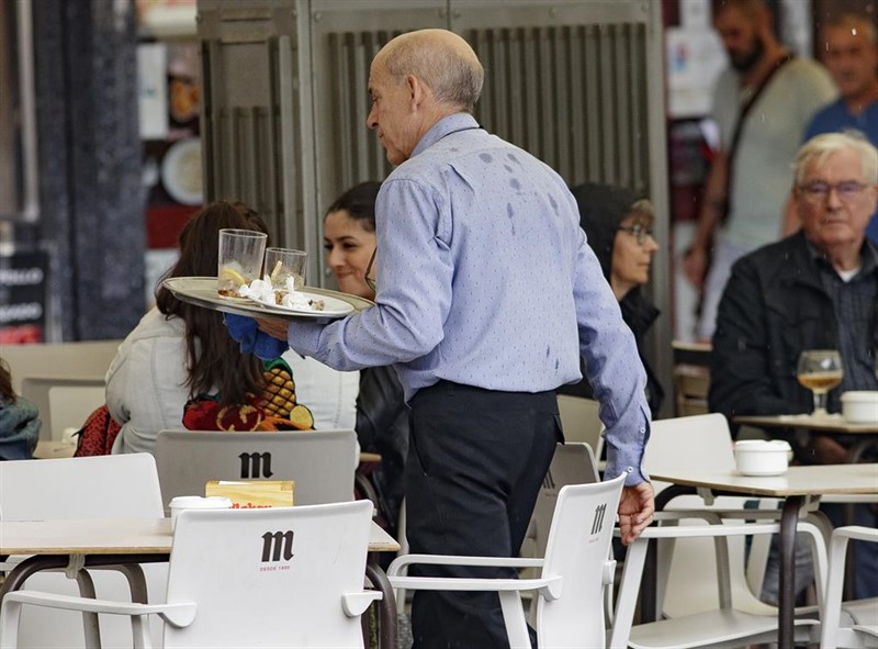 ep un camarero porta una bandeja en una terraza de un bar