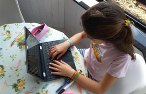 ep una nina haciendo deberes en casa con el ordenador portatil