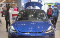 ep imagen de un modelo tesla en un concesionario con personas con mascarillas alrededor
