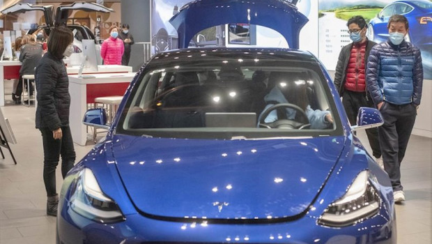 ep imagen de un modelo tesla en un concesionario con personas con mascarillas alrededor