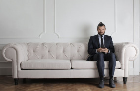 1582673028 man sitting on white couch using smartphone 3756987