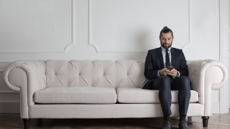 1582673028 man sitting on white couch using smartphone 3756987