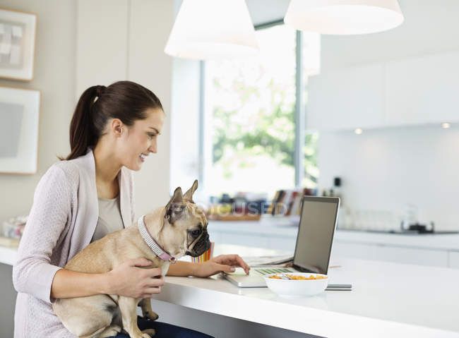 1593430913 focused199749270 stock photo woman using laptop dog lap