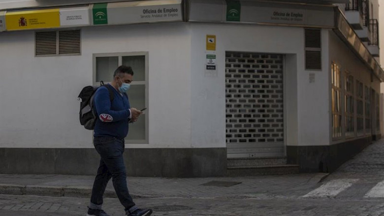 ep un hombre protegido con mascarilla camina delante de una oficina de empleo